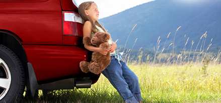 Barn bak på en bil i solen